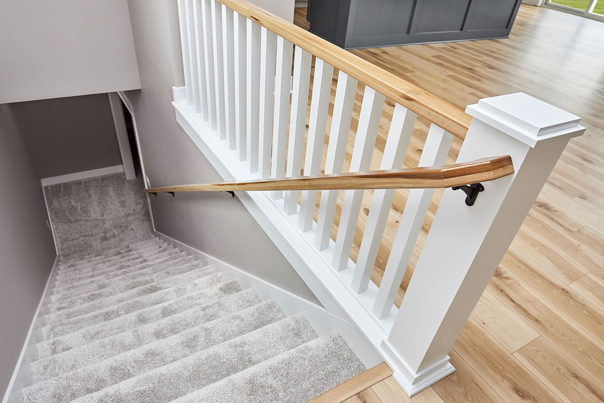Carpet stair runway with brown stair railings and white painted banister