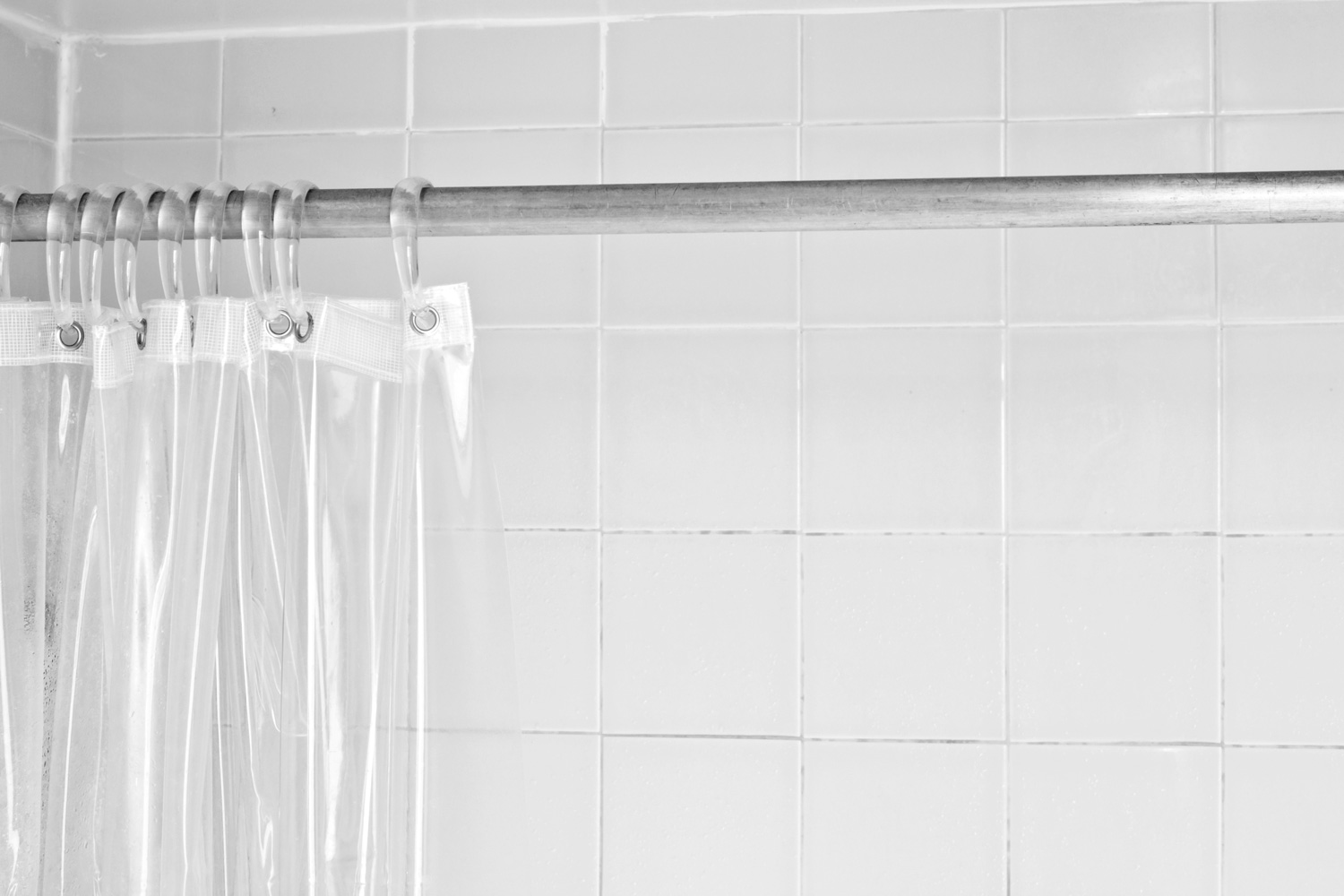 Clear shower curtain with a white tile shower