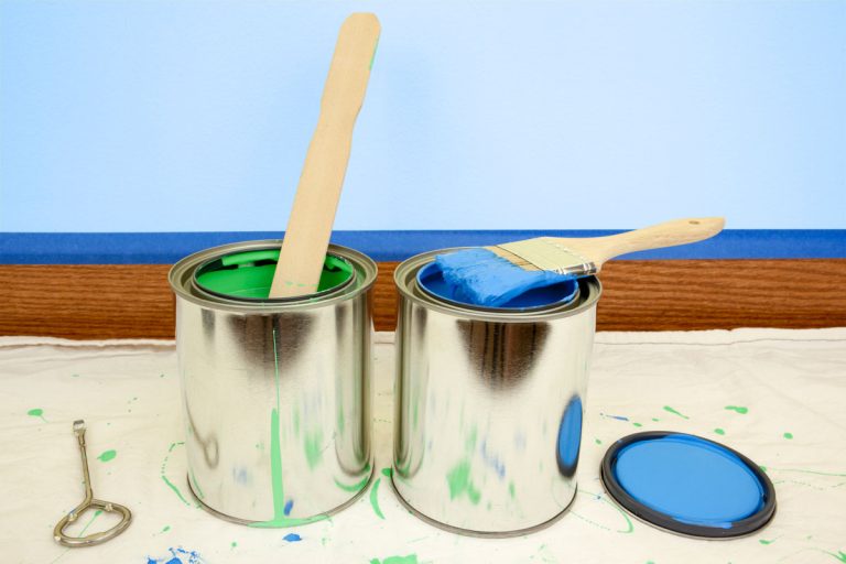 Close-up of open cans of blue and green paint. In the background, a light blue interior wall prepared with blue painters tape provides copy space, Benjamin Moore Soft Gloss Vs Semi Gloss: What's The Difference?
