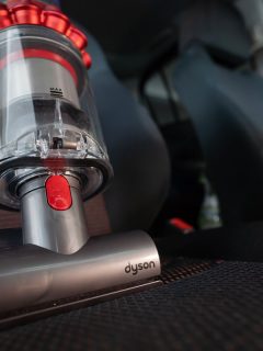 Close up of the Mini motorhead of Dyson Cyclone V10 Fluffy vacuum cleaner on car seats with car interior background, How Long Does Dyson Take To Charge?