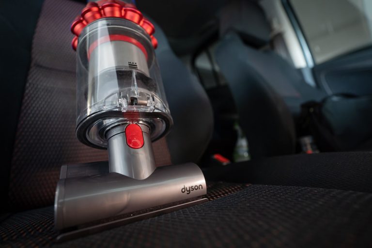Close up of the Mini motorhead of Dyson Cyclone V10 Fluffy vacuum cleaner on car seats with car interior background, How Long Does Dyson Take To Charge?