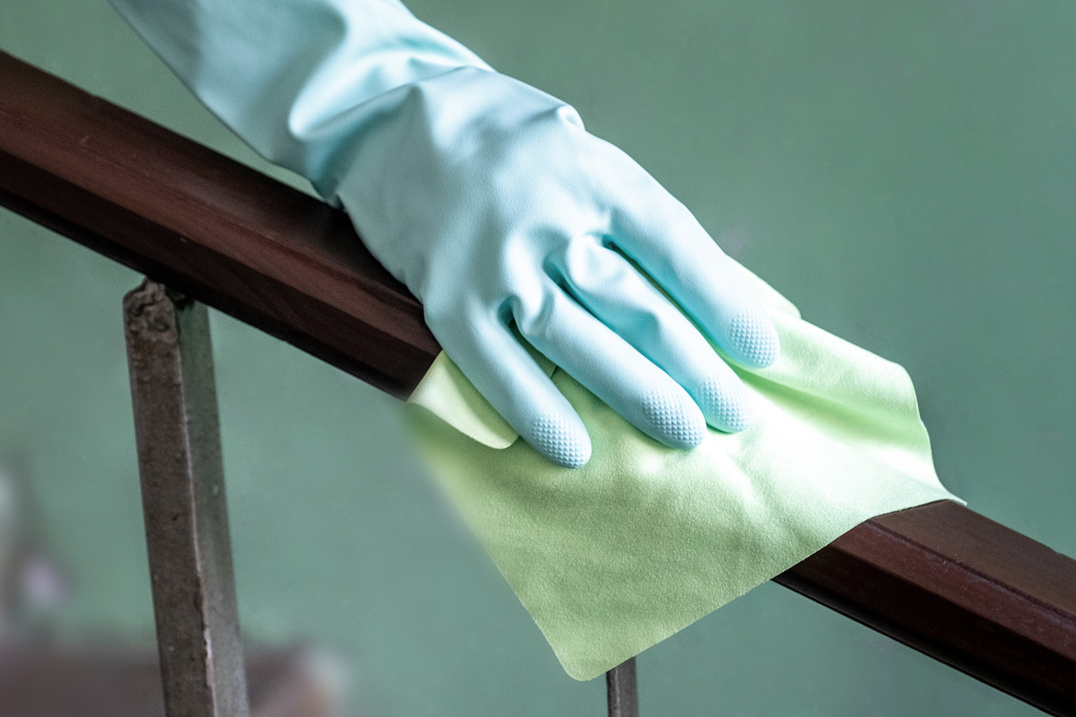 Closeup view of a woman's hand using an antibacterial wet wipe for disinfecting the railing on the flying cage.