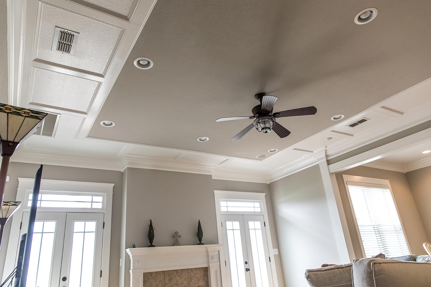 Detailed trim white wood tray ceiling with a ceiling fan
