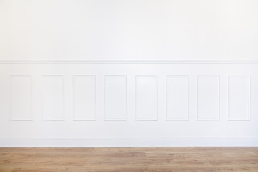 Empty white room with parquet floor and wood trimmed wall