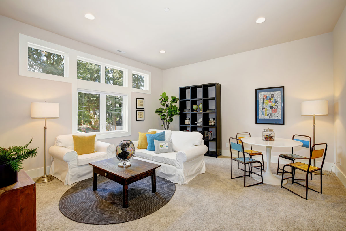 Family room and playroom features play table, white slipcovered sofa and armchair adorned with bright yellow and blue pillo