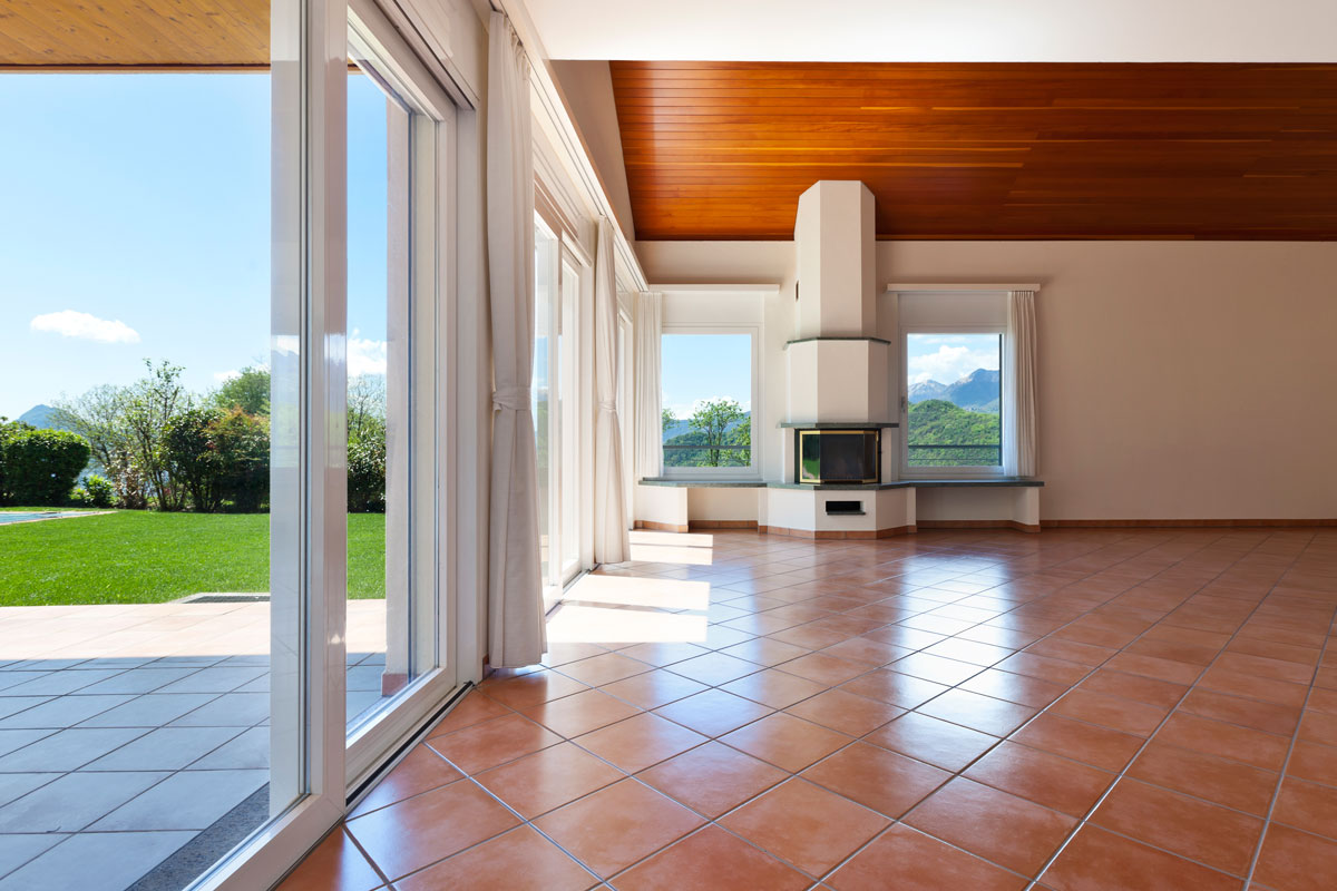 Glass sliding doors and white curtains with terracotta tile flooring