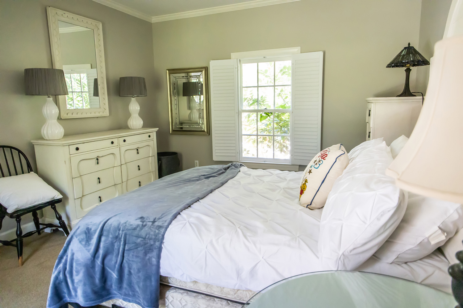 Guest bedroom with white bedding and a blue blanket