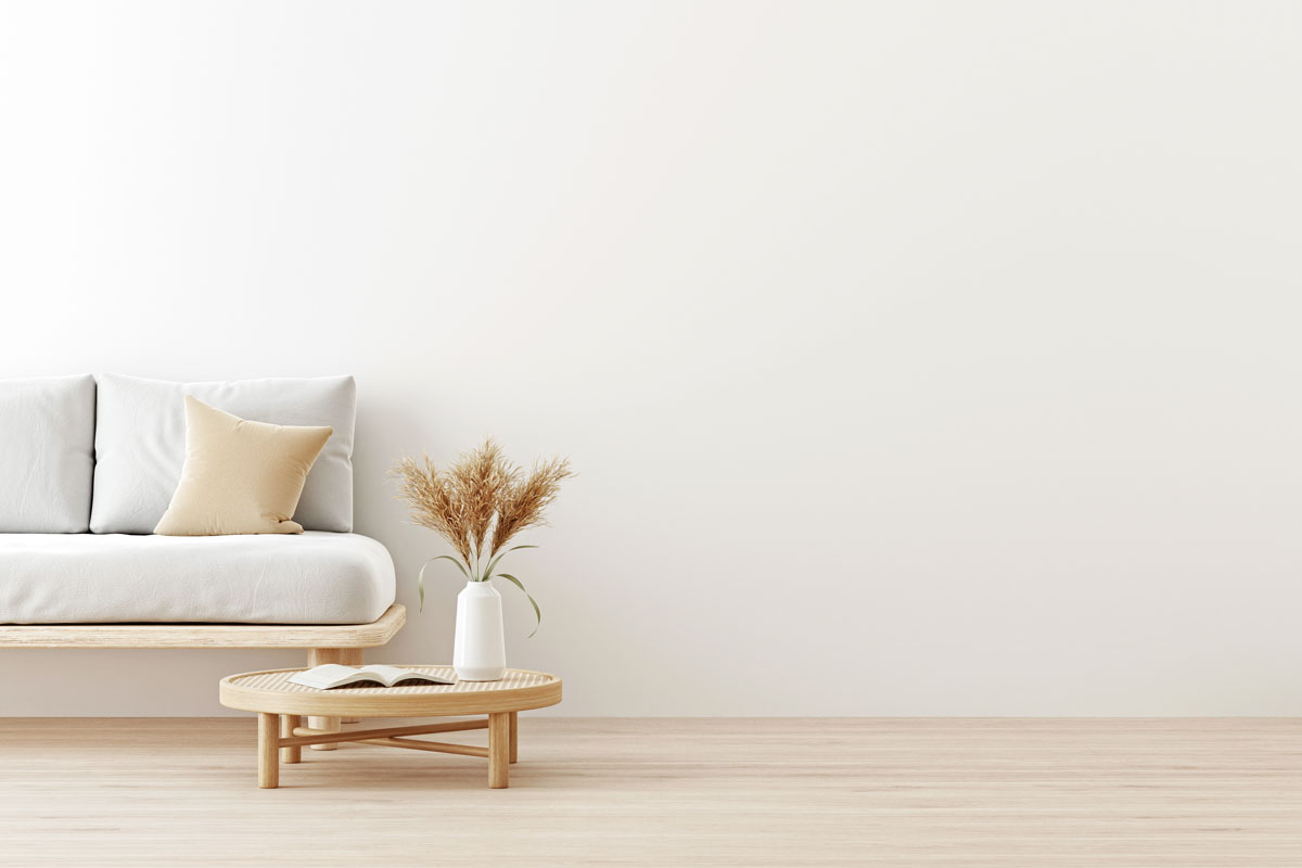 Interior wall mockup in warm neutrals with low sofa, beige pillow and dried Pampas grass on caned table in japandi style living roo