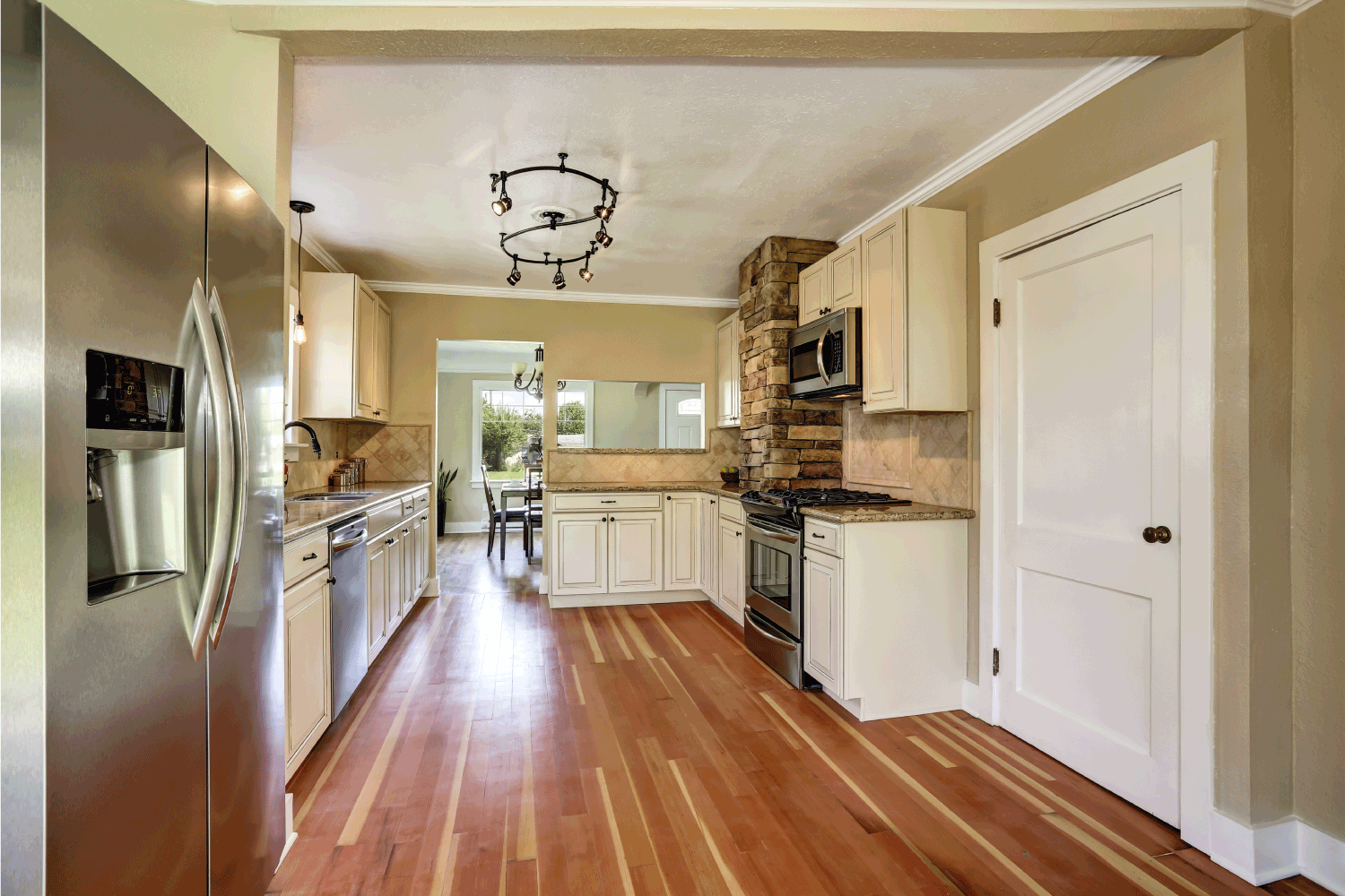 Kitchen room interior with white cabinets, stainless steel and hardwood floor. Heart Wood And Near-Bark Wood