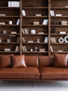 Leather sofa with cushions standing on living room with stylish interior design and collections books on bookshelves, How To Stop Feathers From Coming Out Of Couch