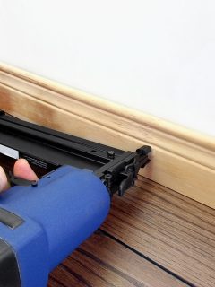 Male hand with carpenter tool installing baseboard - What Type And Size Nails For Baseboards