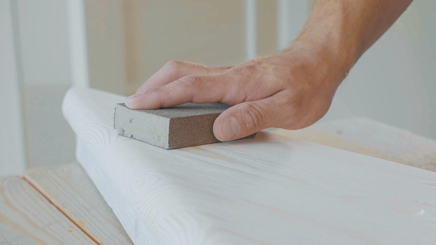 Male hands polishing wooden step with sandpaper