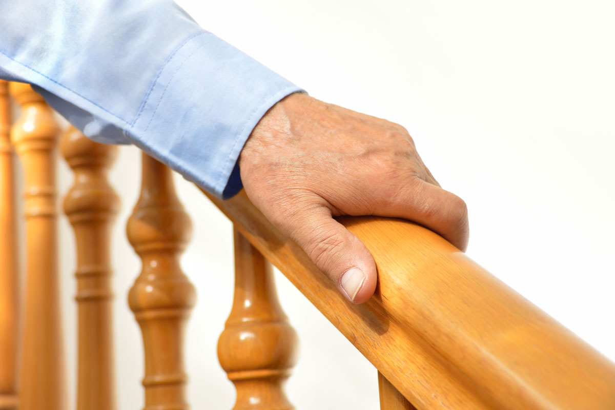 Mans hand holding the wooden handrail