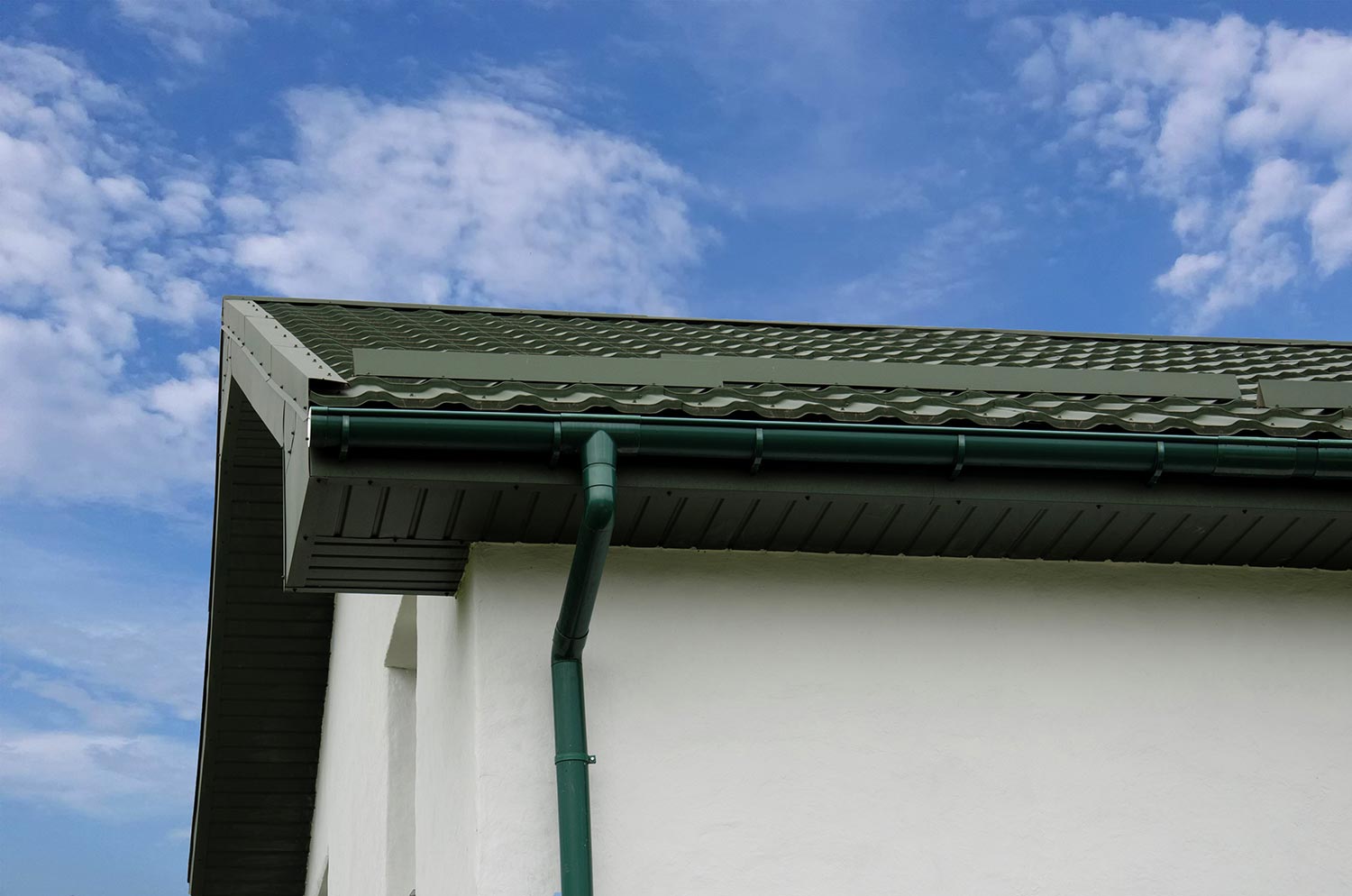 Metal roof tile with plastic gutter system against blue sky