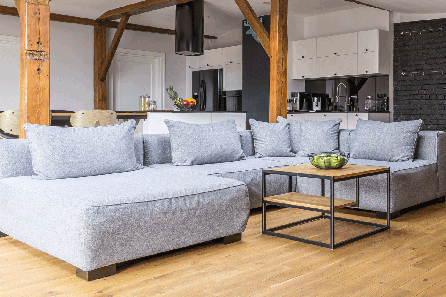Modern loft open space apartment with wooden beams and floor, simple modern furniture, gray sofa, coffee table, brick wall. Second Tone As Fireplace Accent