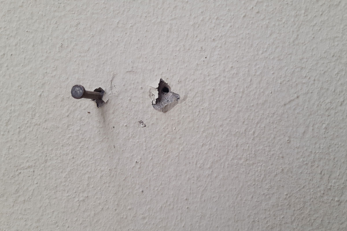 Nail holes and concrete nail left on the wall