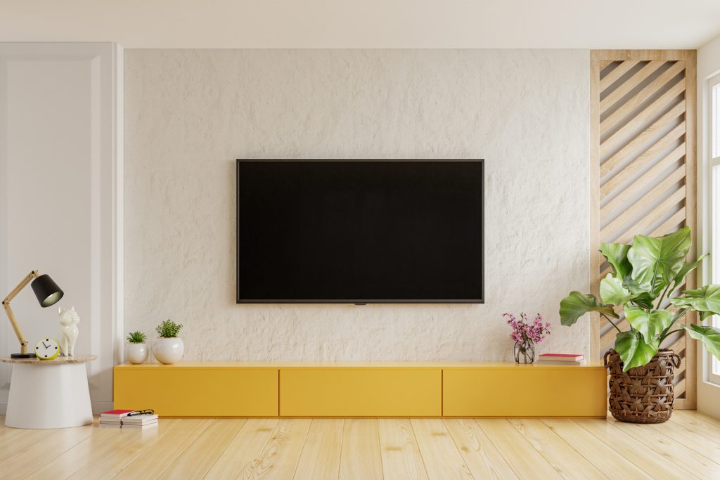 On a plaster wall background, a TV is mounted on a yellow cabinet in a modern living room.3D rendering