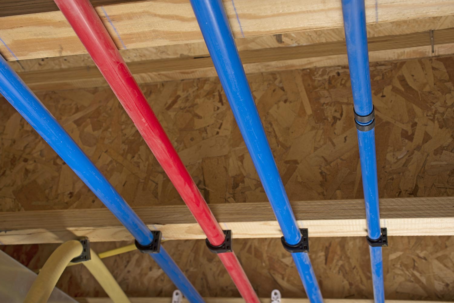 PEX and drain pipes attached to the basement ceiling of a home