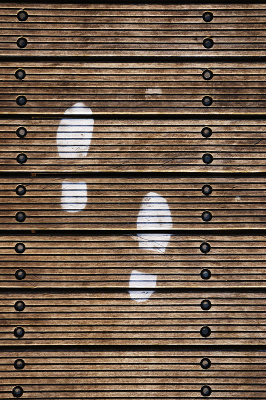Pair of footsteps in white paint on floor boards of Zoutkamp's wooden pier