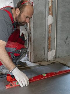 Professional tile worker measuring and leveling the floor with electric laser level, How Much Does It Cost To Level A Floor?