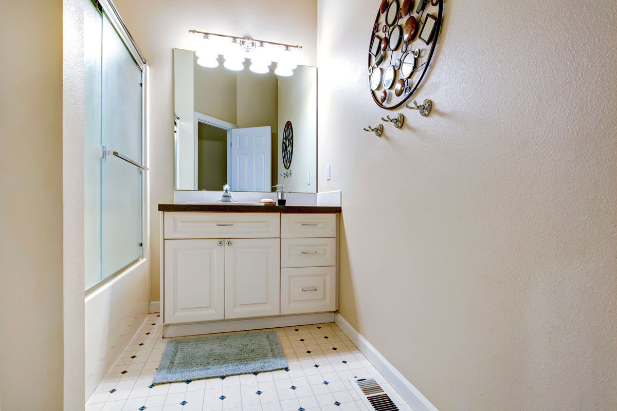 Rectangle bathroom with vanity, mirror and wall decorated with art frame and hangers