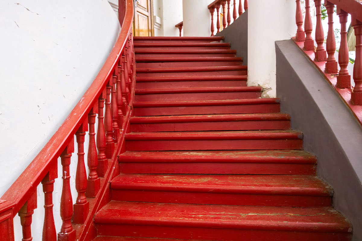 Red painting stairs and stair railing inside a white mansion