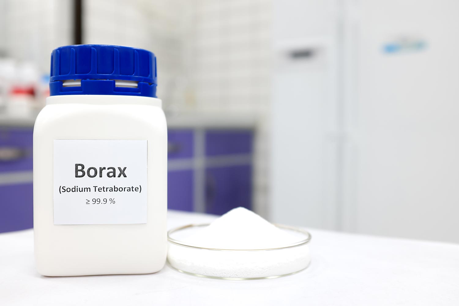Selective focus of a bottle of borax chemical compound or sodium tetraborate beside a petri dish with solid powder substance
