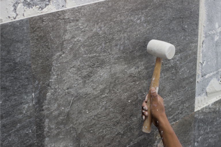 Setting tiles in wall, using rubber mallet. How To Tile A Bathroom Wall With Large Tiles