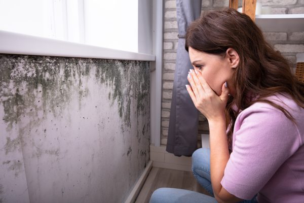Side View Of A Shocked Young Woman Looking At Mold On Wall - How To Get Rid Of Mold On Bedroom Walls