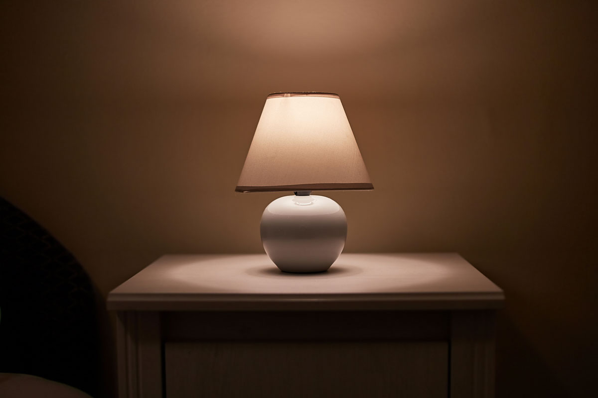 Small lamp glowing in bedroom night stand, dim room