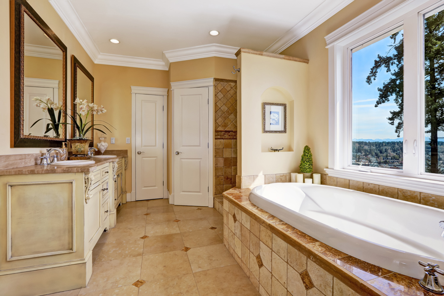 Soft tones bathroom interior with tile floor and tile wall trim, antique vanity with mirror and round bath tub in luxury house