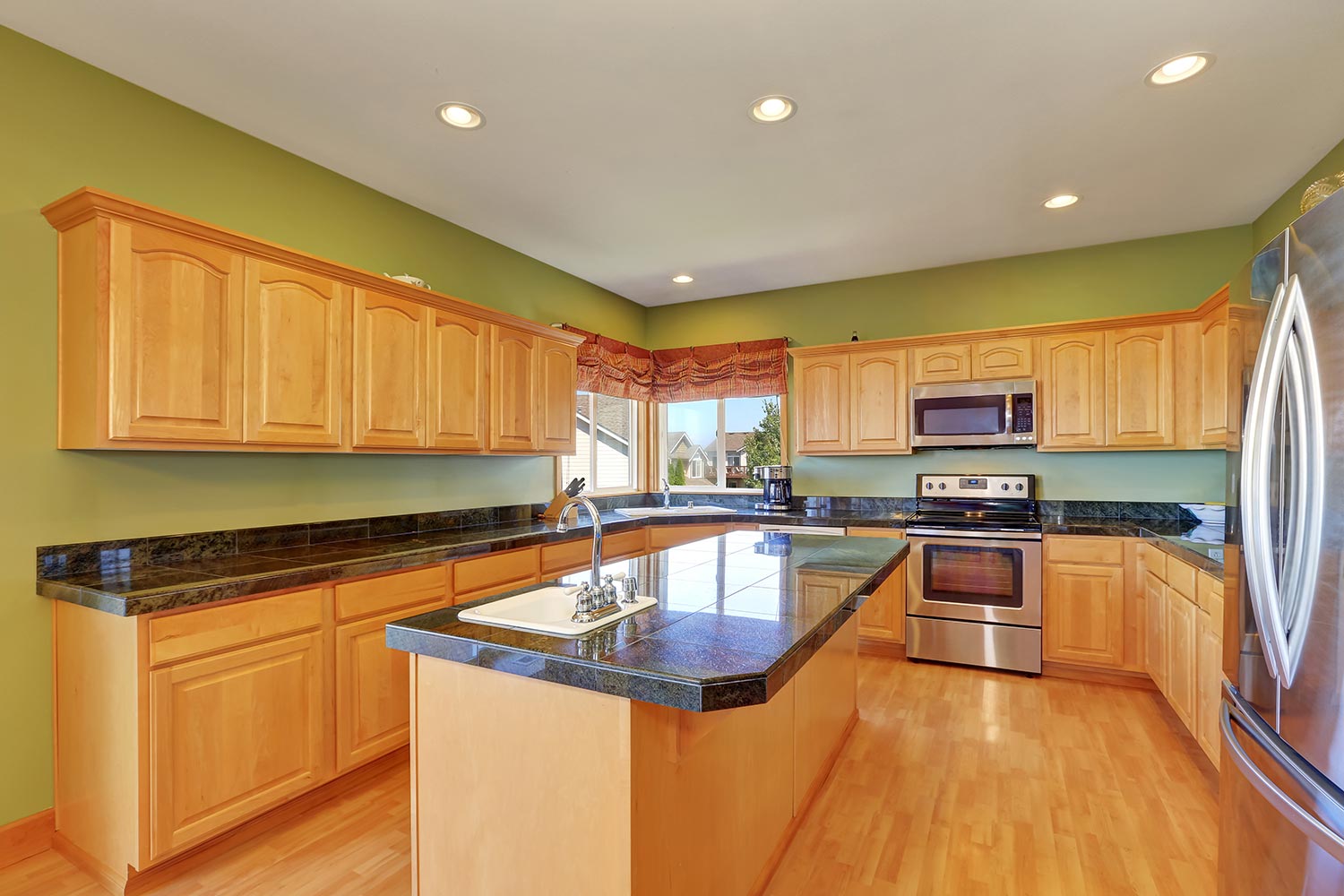 Spacious kitchen with green walls, hardwood floor and maple cabinet