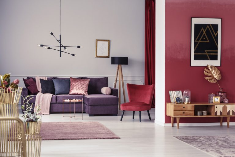 Spacious maroon apartment with corner sofa, red armchair and wooden cupboard - What Color Goes With Maroon [11 Great Color Schemes]