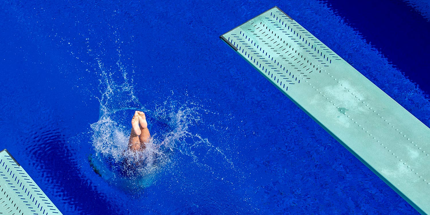 Splash of a springboard diver on a surface of a swimming pool