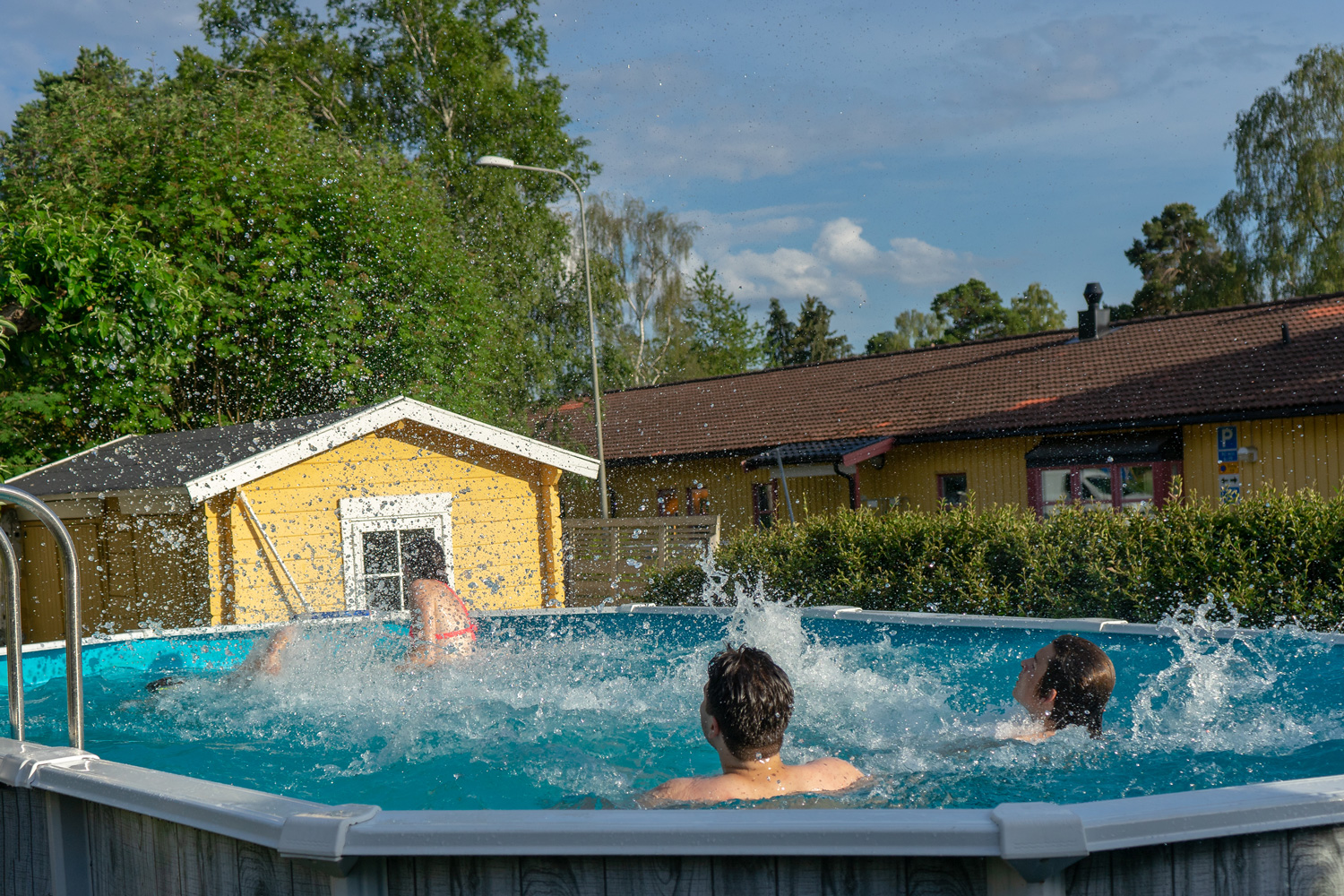 The guys are splashing water on the girls in the pool. Circa Stockholm