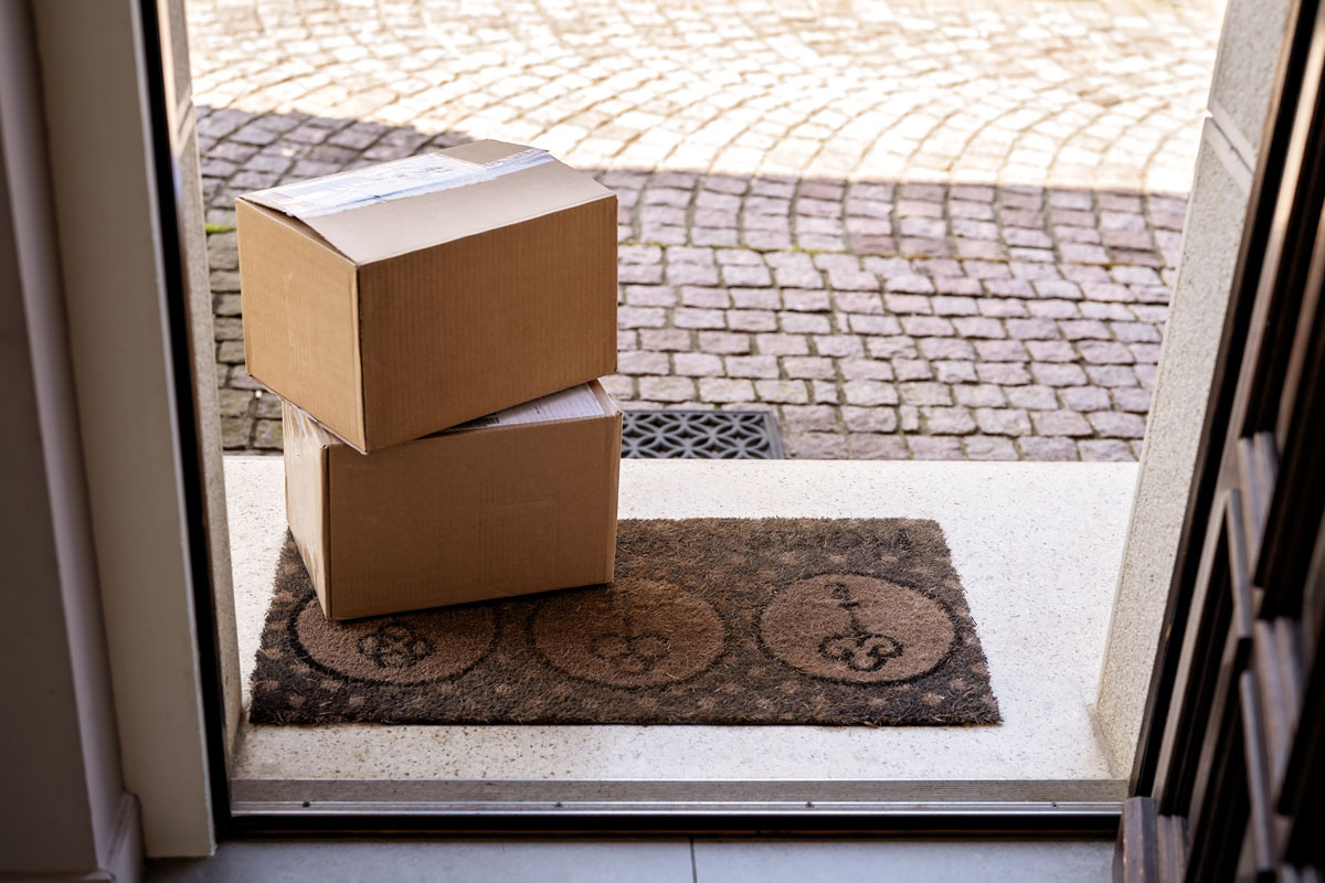 Two cardboard boxes placed on the doormat in front of the door