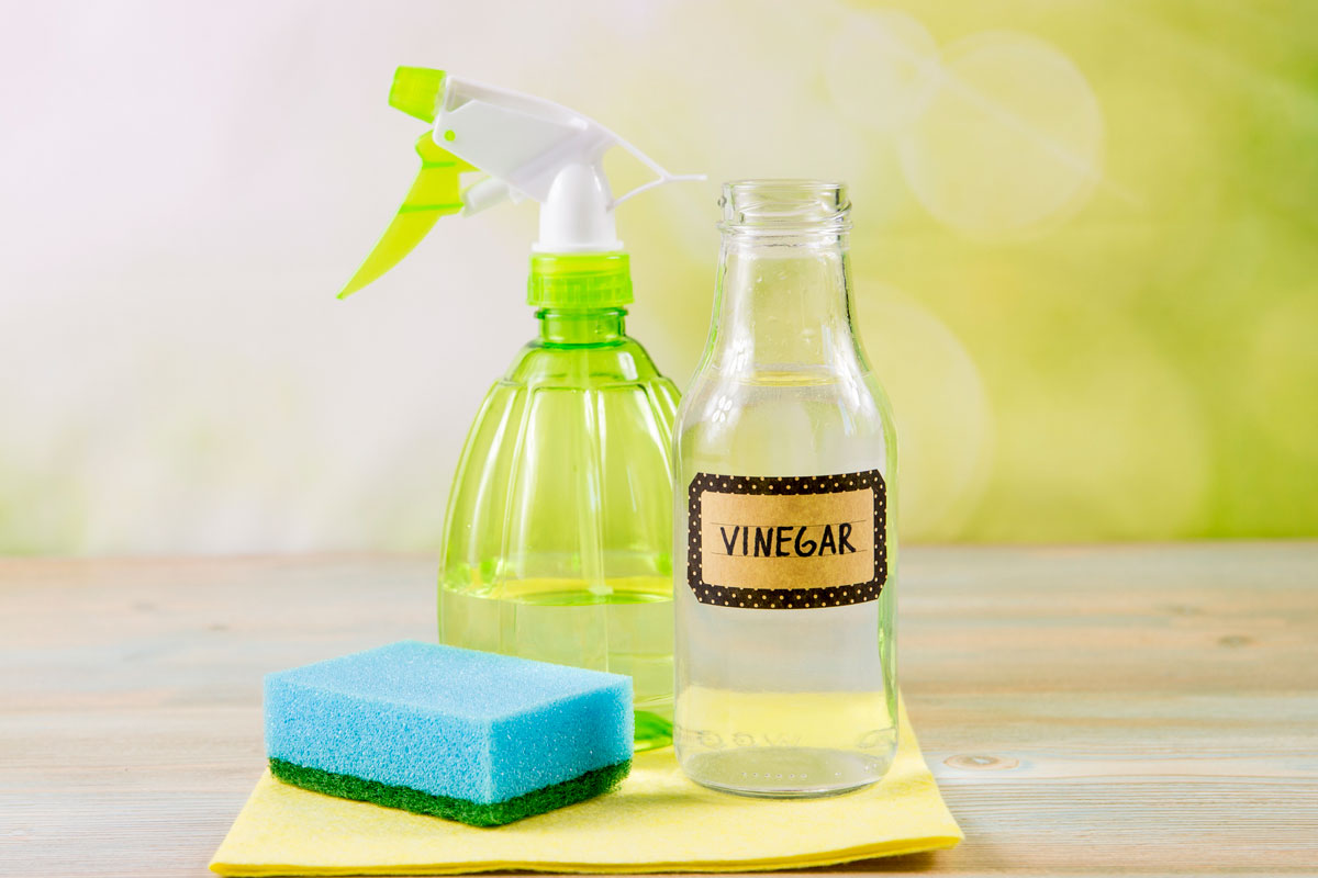Using natural destilled white vinegar in spray bottle to remove stains, tools on wooden table