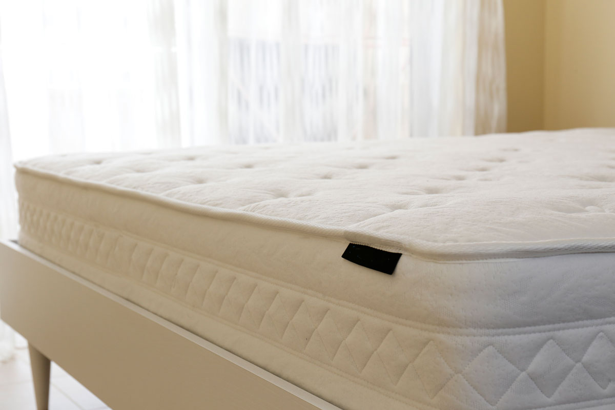 White orthopedic mattress top side surface pattern on unmade bed in the bedroom