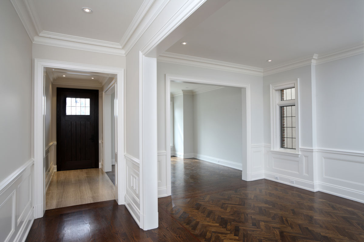 White painted walls with white crown molding and dark colored hardwood flooring