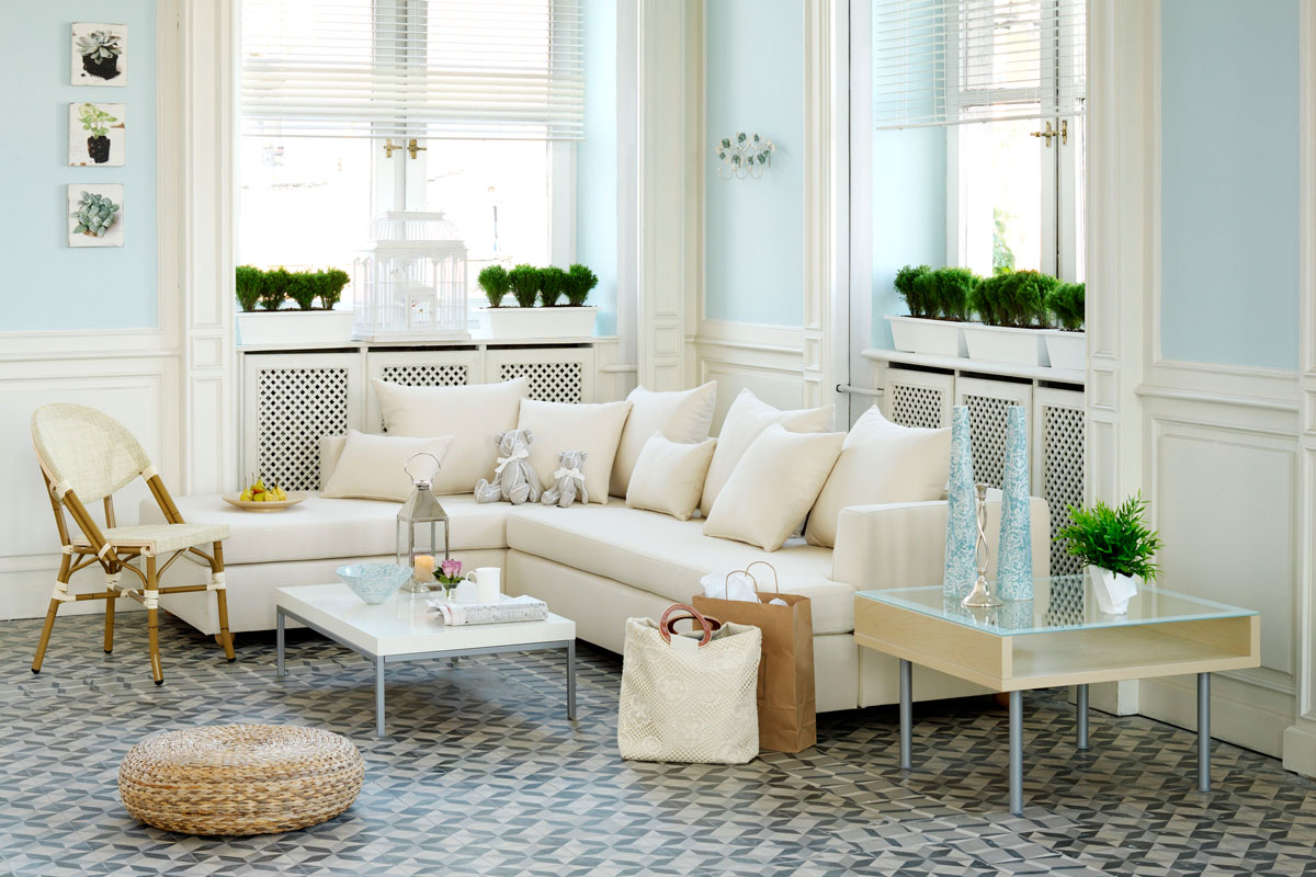 White sectional sofa with white throw pillows and small plants displayed on the window sill