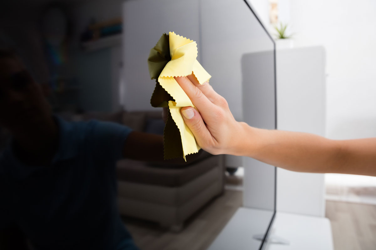 Woman cleaning the TV with a yellow cloth