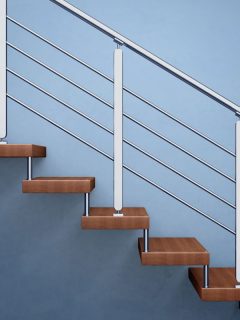 Wooden stairs and metal railing inside a blue walled living room, What Height Should Handrail Be On Stairs?