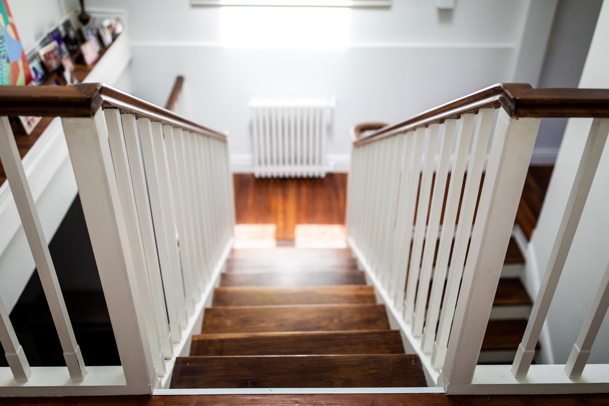 Wooden stairs painted in white with wooden handrails and white banisters