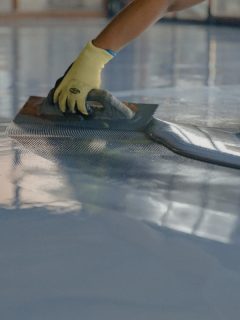 A worker applies gray epoxy resin to the new floor, How To Clean Up After Epoxy Resin