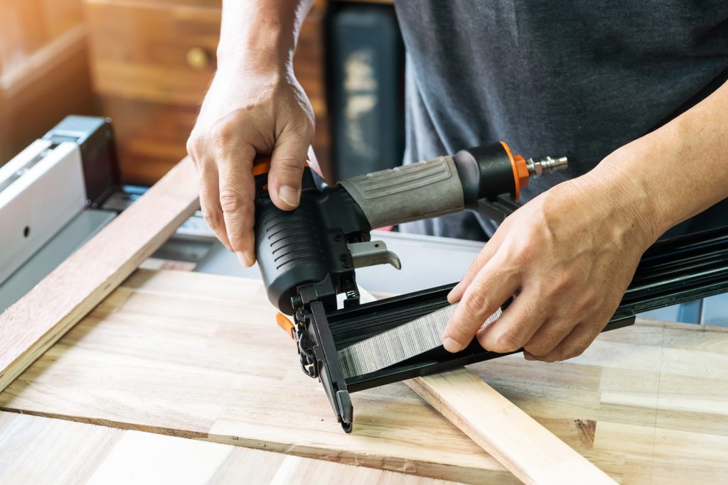 carpenter load nails into a nail gun ,furniture restoration woodworking concept.