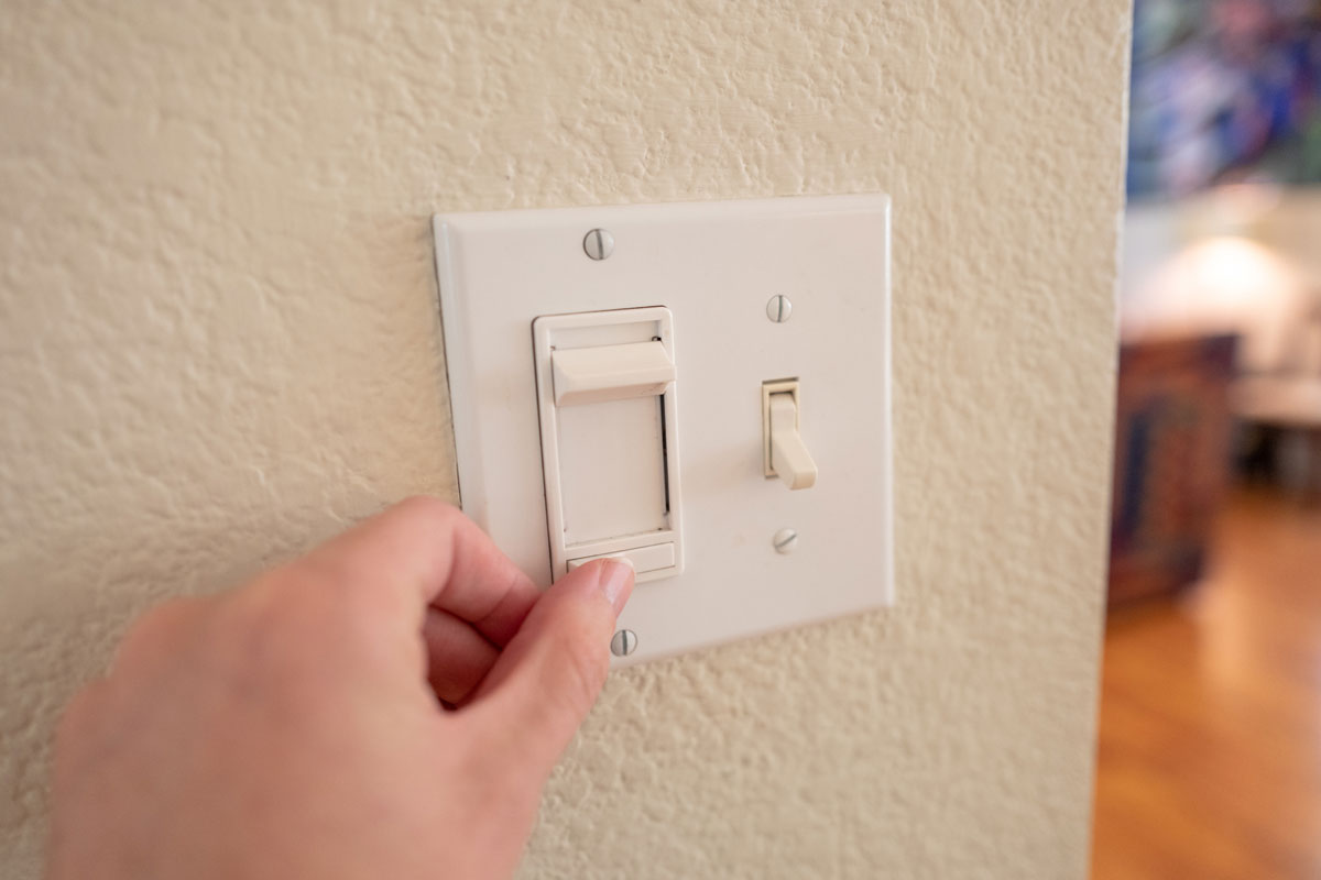 human hand of a man adjusting dimmer switch on wall light switch