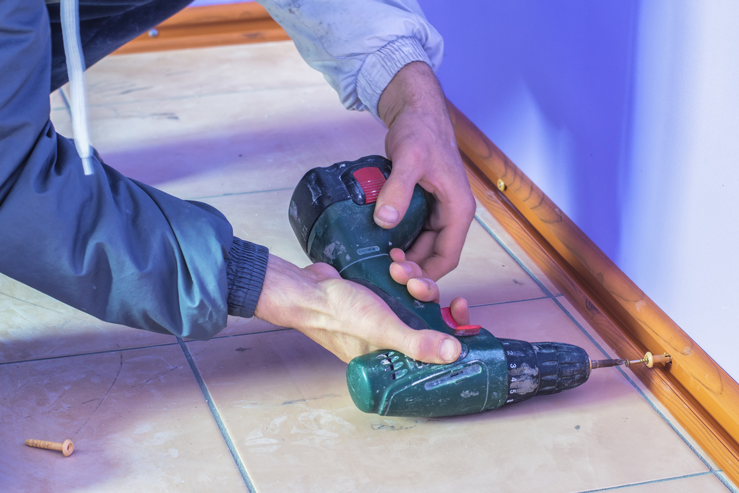 installing baseboards on the floor using a screwdriver