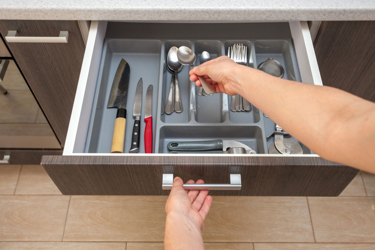 person pov view woman hand open new brown kitchen drawer by modern door handle, with different cutlery take spoon to prepare
