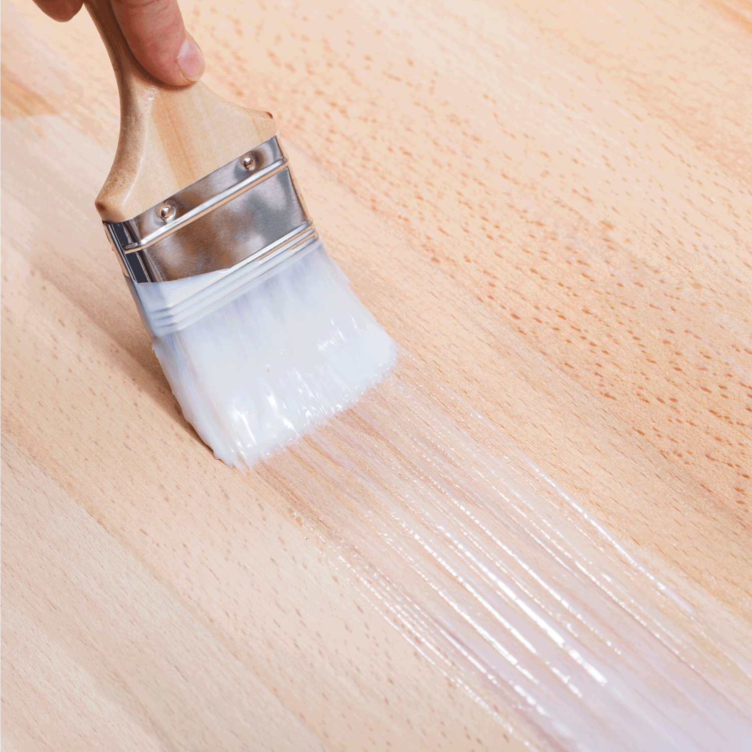 putting layer of clear lacquer on surface of beech top table by paint brush