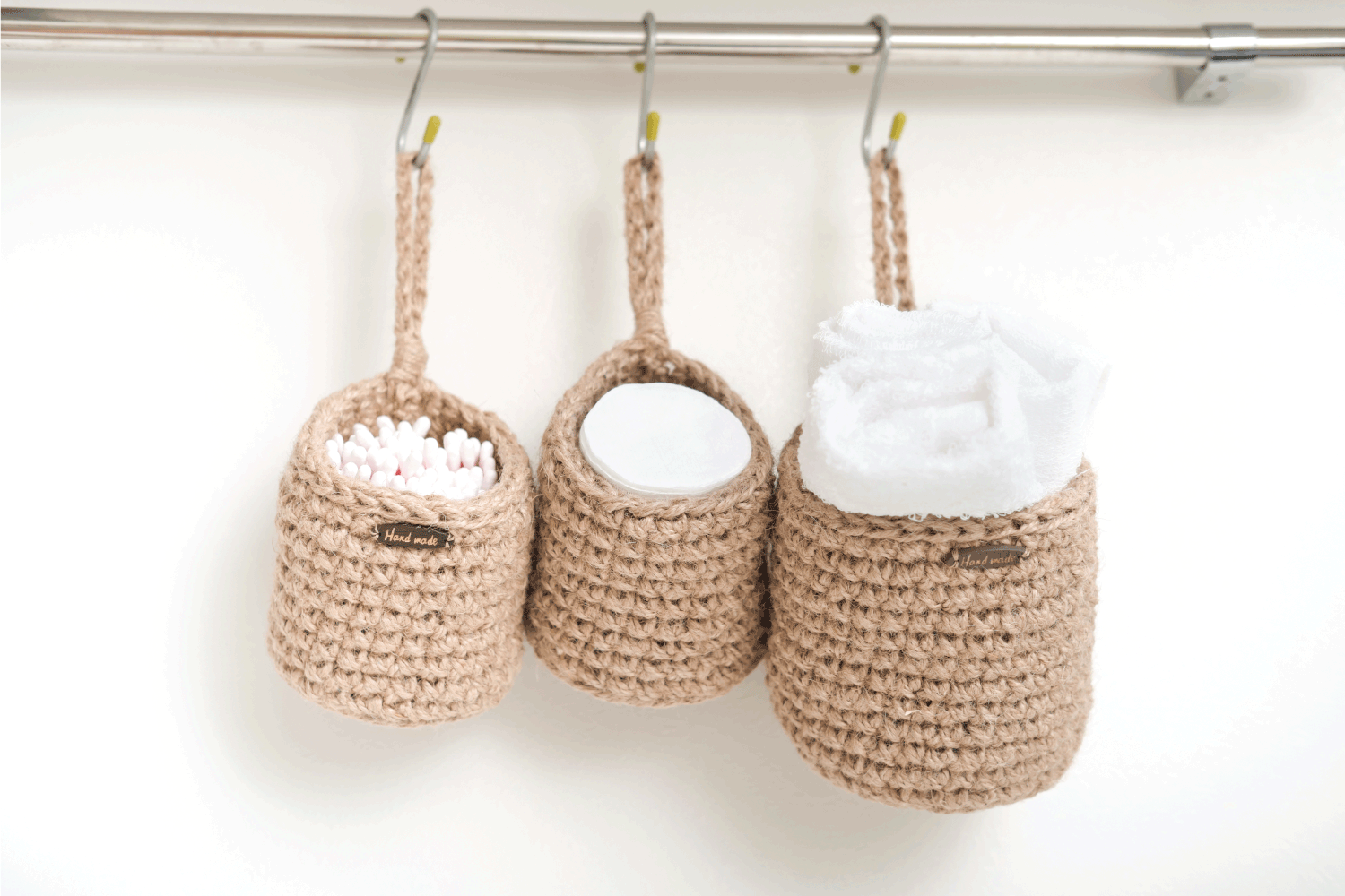 three wicker mini baskets hanging on a wall. toiletry storage in bathroom. eco natural jute hand made basket. cozy scandinavian style